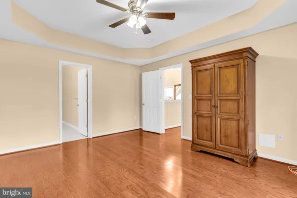an empty room with wooden floor closet and windows