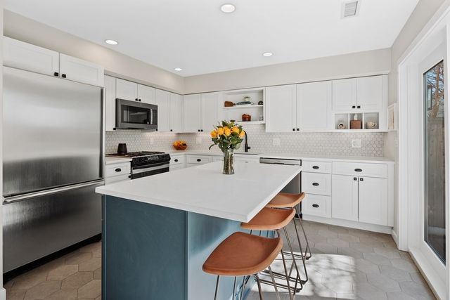 a kitchen with stainless steel appliances kitchen island a refrigerator sink and cabinets