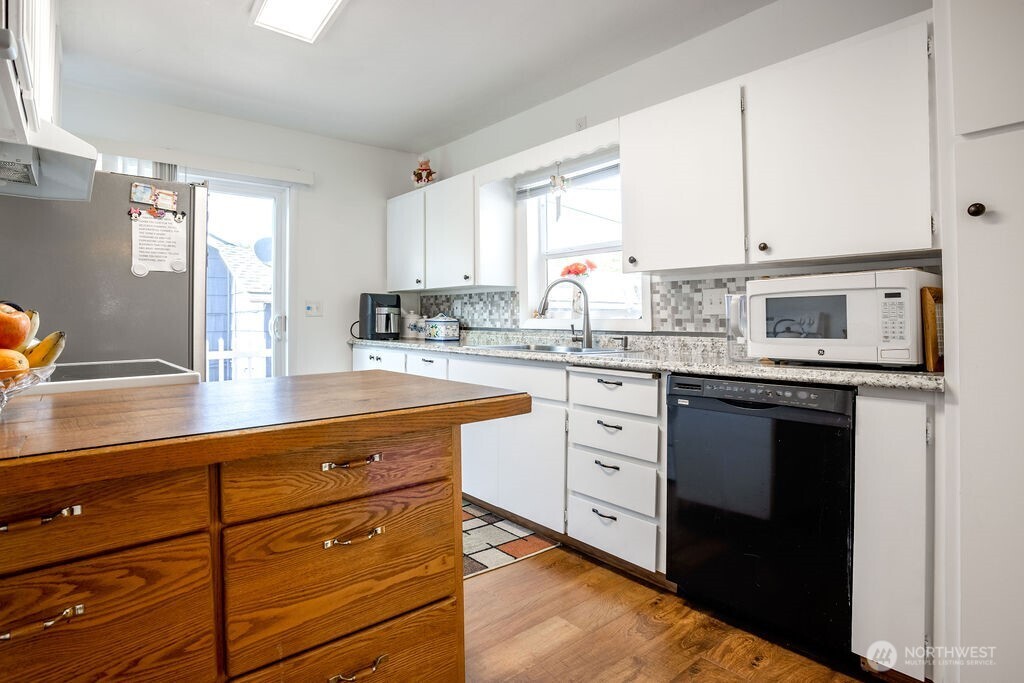 404 Jackson Street Ryderwood, WA 98581 - Photo 13 of 27 a kitchen with stainless steel appliances granite countertop a sink dishwasher stove and white cabinets with wooden floor