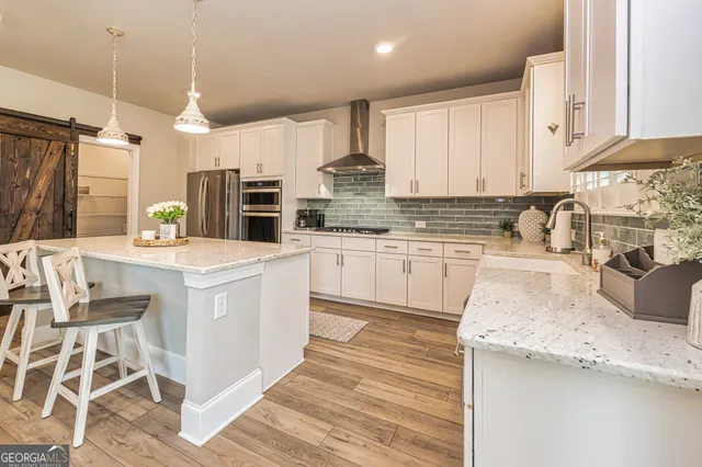 a kitchen with stainless steel appliances kitchen island granite countertop a sink cabinets and wooden floor