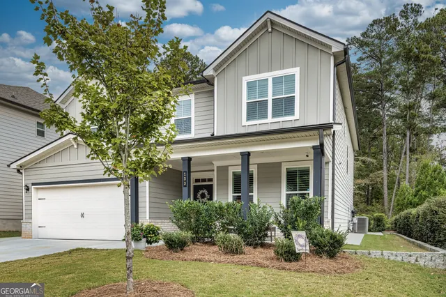 a view of a yard in front of a house with plants and large tree