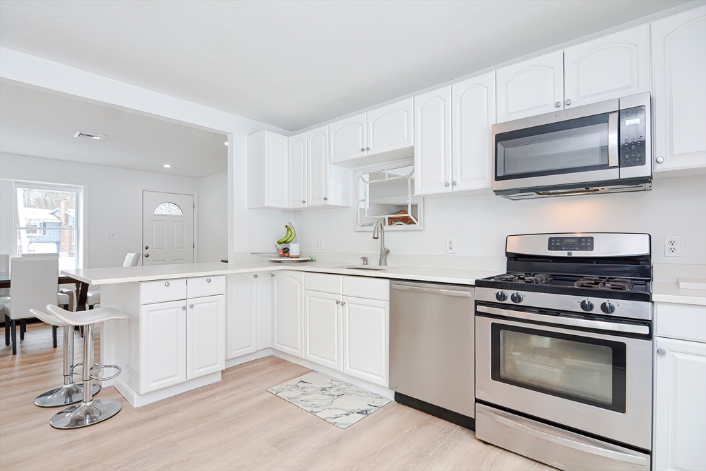 257 Brook Circle Hanover, MA 02339 - Photo 6 of 23 a kitchen with cabinets stainless steel appliances and wooden floor
