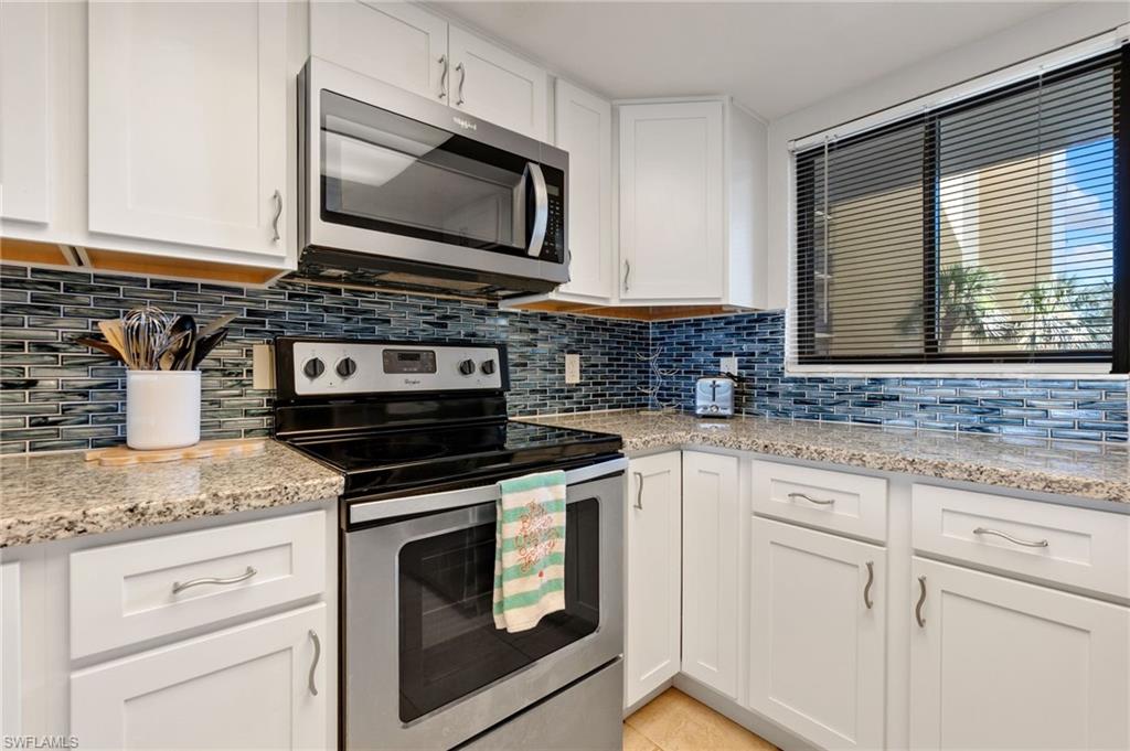 400 Lenell Road, Unit 110 Fort Myers Beach, FL 33931 - Photo 13 of 37 a kitchen with granite countertop white cabinets appliances and a counter space