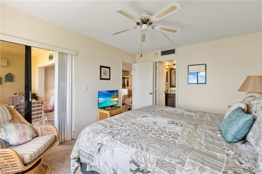 400 Lenell Road, Unit 110 Fort Myers Beach, FL 33931 - Photo 19 of 37 a bedroom with a bed a couch and a chandelier