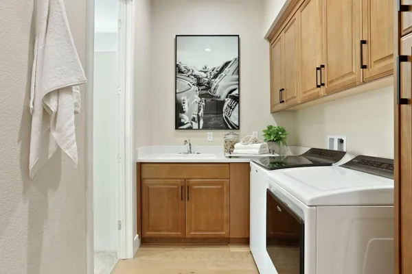 a utility room with stainless steel appliances white cabinets and a sink