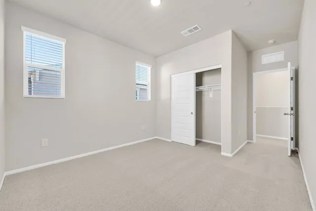 a view of an empty room with closet and a window