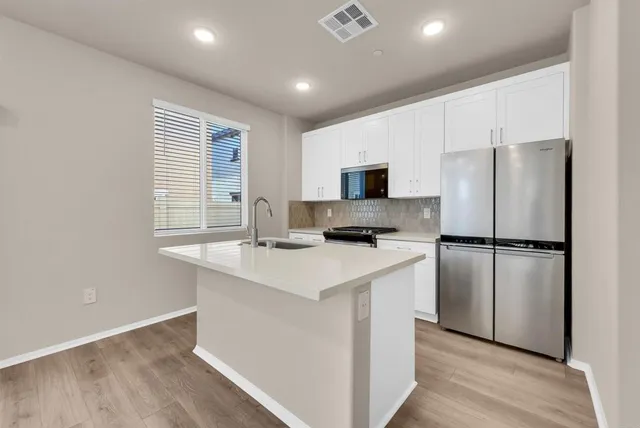 a kitchen with white cabinets and stainless steel appliances