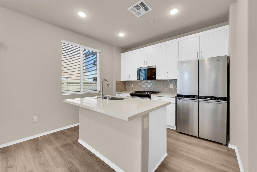28381 Via Solero Temecula, CA 92591 - Photo 9 of 28 a kitchen with white cabinets and stainless steel appliances