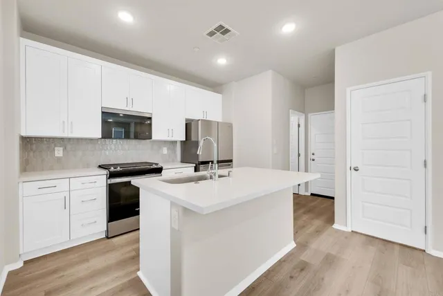 a kitchen with a sink a stove a refrigerator and cabinets