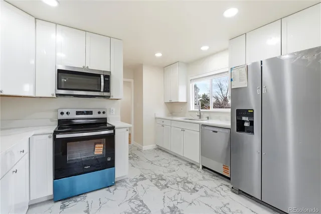 a kitchen with granite countertop a refrigerator stove and microwave