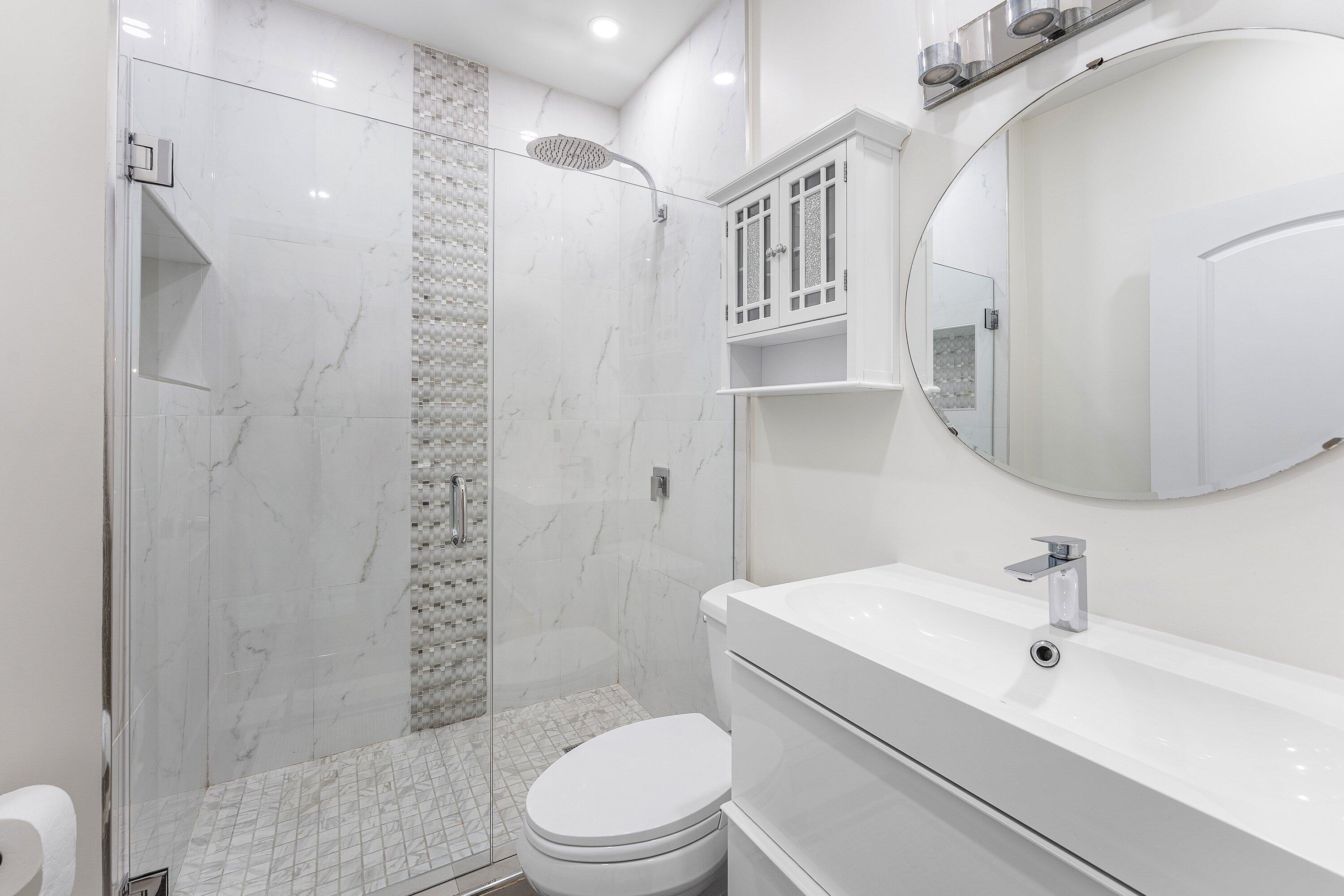 20 South Lakeshore Drive, Unit C Hypoluxo, FL 33462 - Photo 16 of 55 a bathroom with a toilet sink shower and mirror