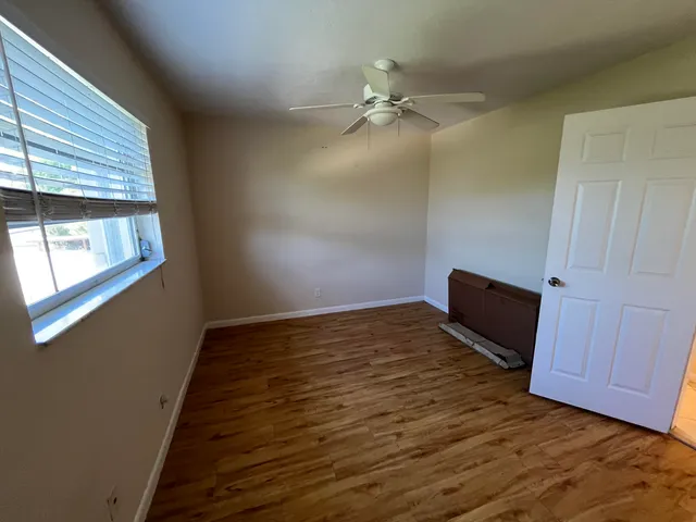 a view of an empty room with wooden floor and a window