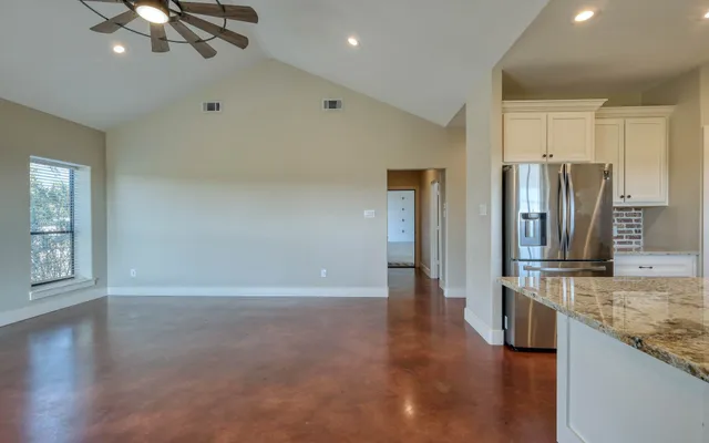 a view of an empty room and kitchen with a ceiling fan
