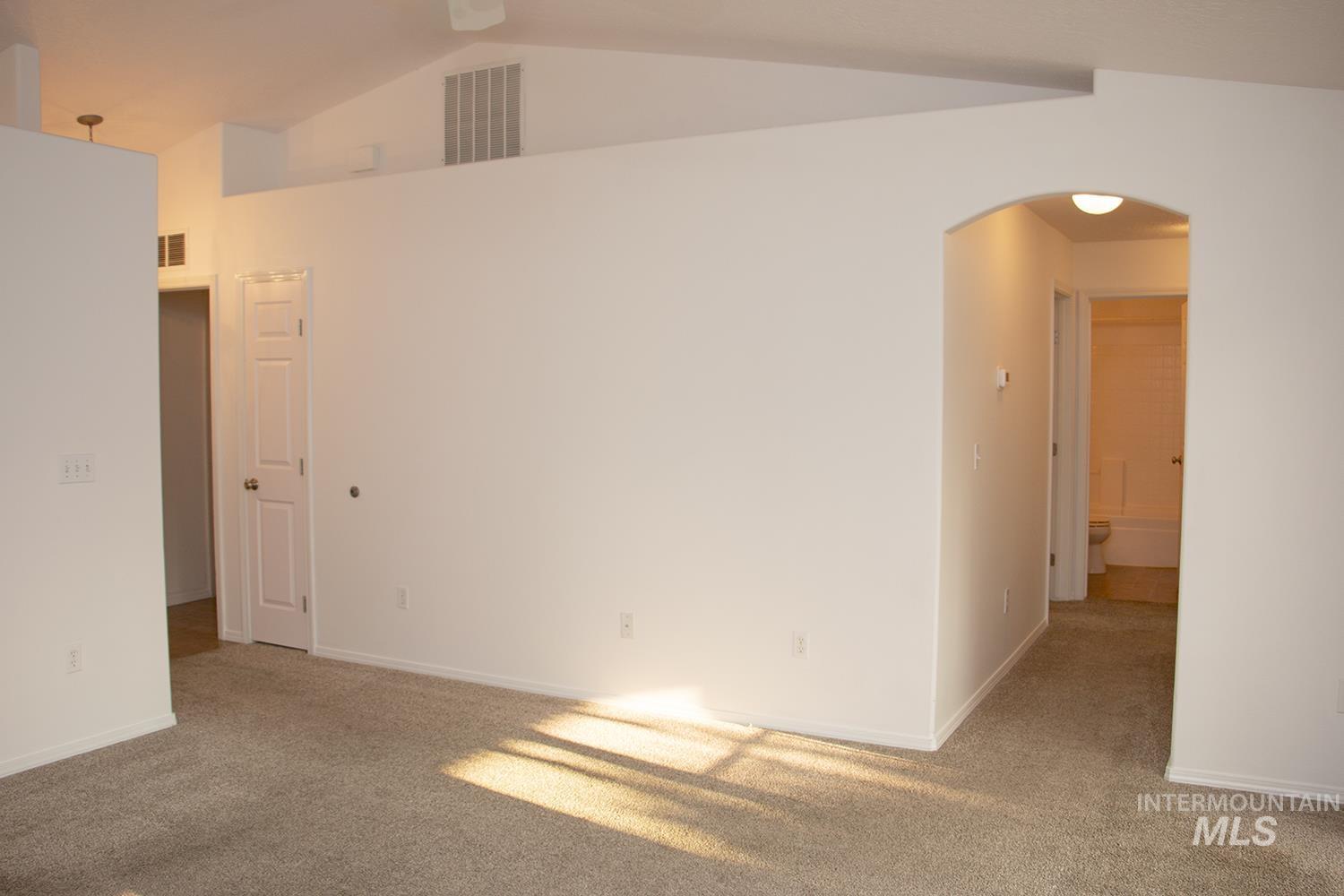 16559 Bayou Way Caldwell, ID 83607 - Photo 11 of 20 Vaulted ceiling with an upper wall vent, arched entryway, white interior doors, and neutral carpet flooring