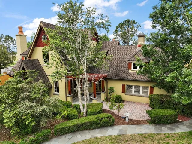 a view of a brick house with plants and large tree
