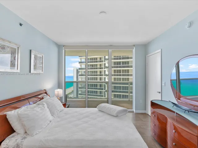 a bedroom with a large bed and a flat tv screen on dresser