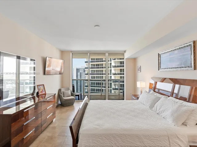 a bedroom with a bed a couch and a dresser next to a window