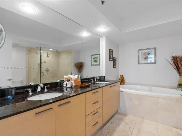 a spacious bathroom with a granite countertop double vanity sink a mirror and a bathtub