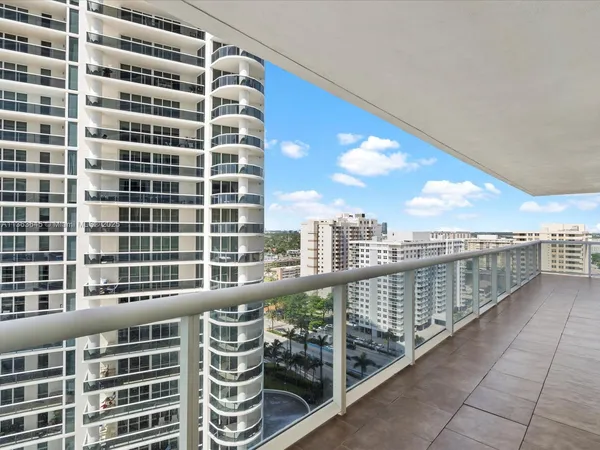 a view of a balcony with a floor to ceiling window next to a tall building