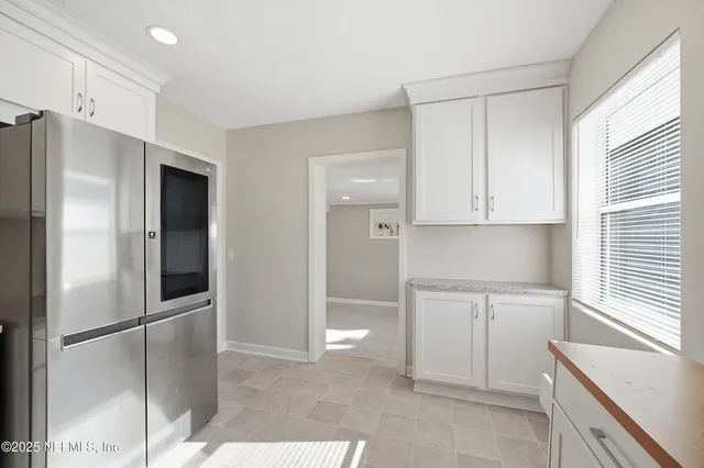 a kitchen with white cabinets and refrigerator