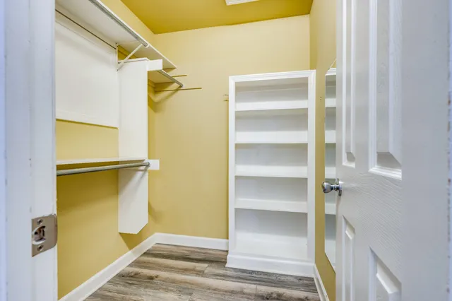 a view of an empty room with wooden floor and a ceiling fan
