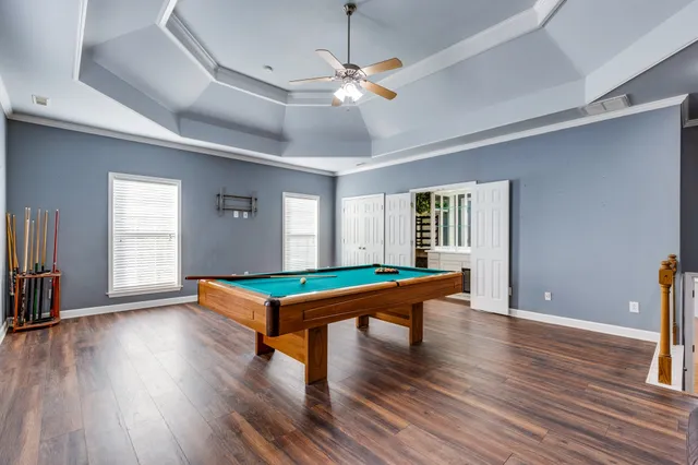 a room with wooden floor pool table and chairs