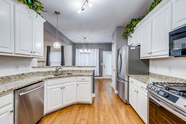 a kitchen with granite countertop a sink a stove refrigerator and microwave