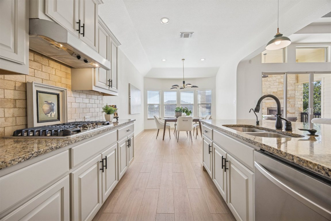 3329 Eagle Ridge Lane Pflugerville, TX 78660 - Photo 13 of 35 Kitchen featuring light stone countertops, appliances with stainless steel finishes, pendant lighting, decorative backsplash, and recessed lighting