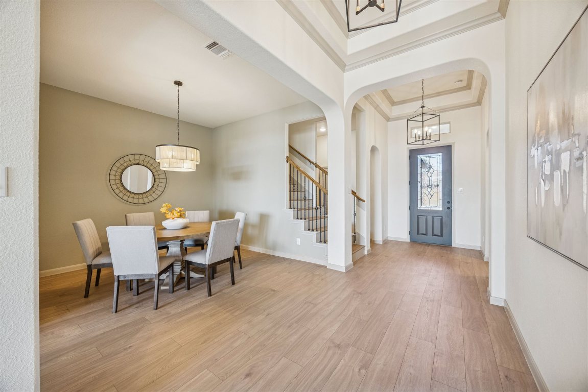 3329 Eagle Ridge Lane Pflugerville, TX 78660 - Photo 4 of 35 Entryway with a chandelier, a tray ceiling, arched walkways, light wood finished floors, and stairway