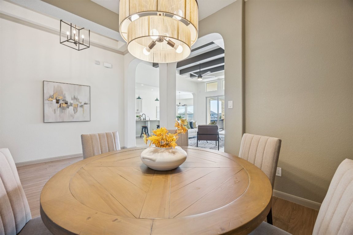 3329 Eagle Ridge Lane Pflugerville, TX 78660 - Photo 5 of 35 Dining area with arched walkways, wood finished floors, and a chandelier