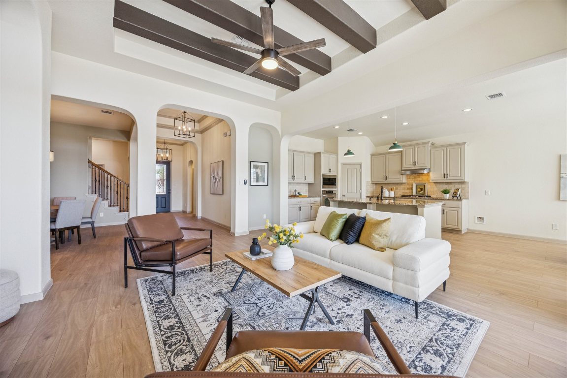 3329 Eagle Ridge Lane Pflugerville, TX 78660 - Photo 9 of 35 Living room with stairway, arched walkways, light wood finished floors, a ceiling fan, and beam ceiling