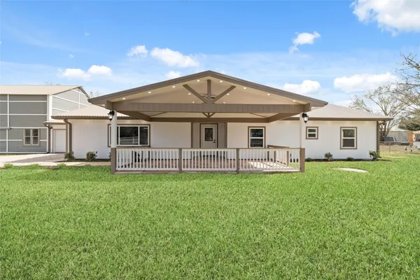 a view of a white house with a big yard and large trees