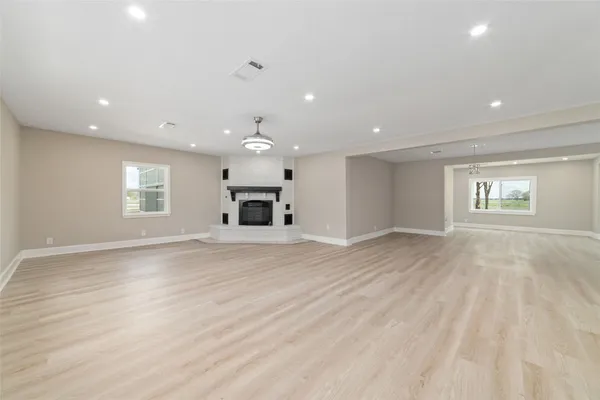an empty room with wooden floor a ceiling fan and windows