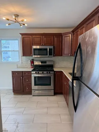 a kitchen with stainless steel appliances granite countertop a stove top oven a sink and a refrigerator