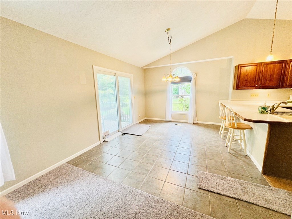1467 Bennett Road Madison, OH 44057 - Photo 15 of 26 Kitchen featuring light tile patterned flooring, lofted ceiling, decorative light fixtures, an inviting chandelier, and a breakfast bar area