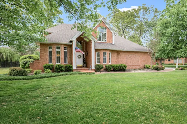 a front view of a house with a yard and trees