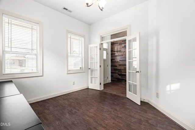 a view of empty room with wooden floor and fan
