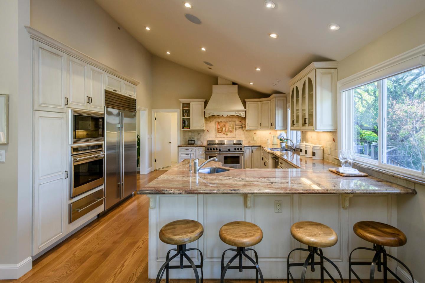 2950 Summit Drive Hillsborough, CA 94010 - Photo 4 of 27 a kitchen with stainless steel appliances granite countertop a table chairs sink refrigerator and microwave