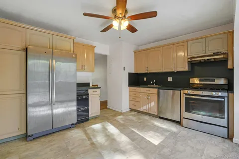 a kitchen with granite countertop a refrigerator a sink a stove and cabinets