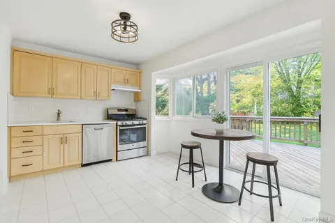 a kitchen with a stove a sink and white cabinets with wooden floor