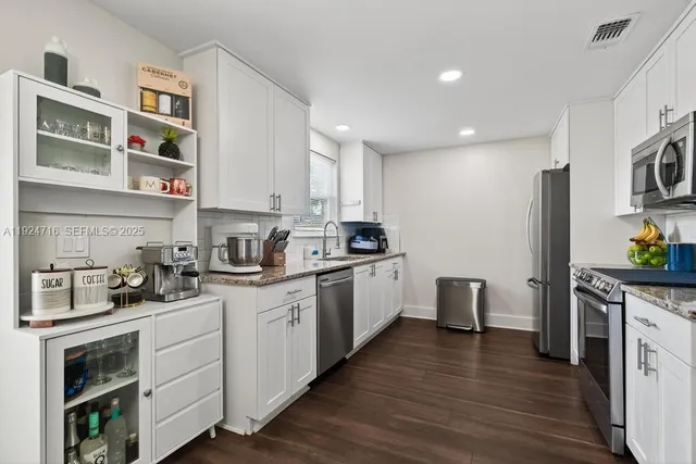 a kitchen with granite countertop cabinets stainless steel appliances and wooden floor