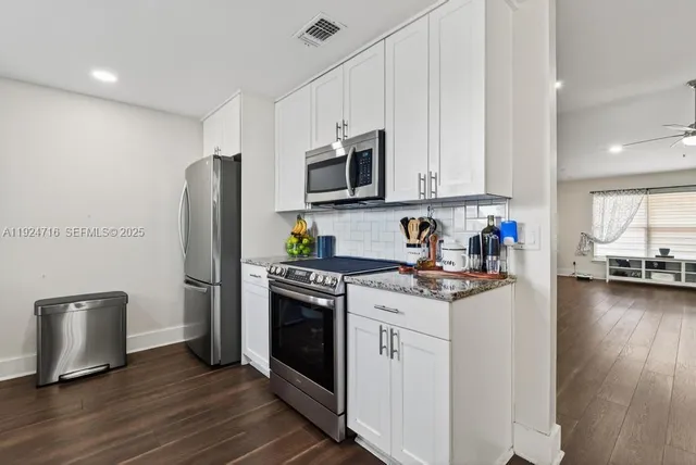 a kitchen with stainless steel appliances white cabinets and a stove top oven
