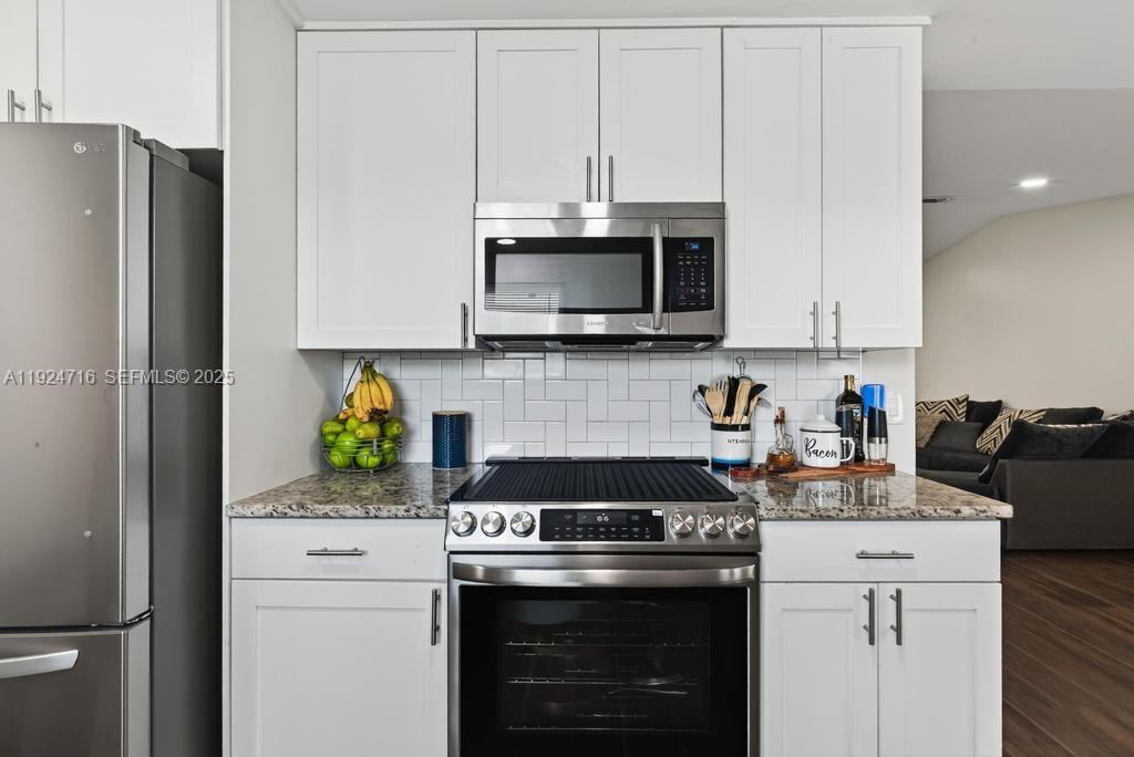 8210 Sailmaker Lane Jacksonville, FL 32210 - Photo 33 of 61 a kitchen with stainless steel appliances granite countertop a stove a refrigerator a microwave a sink and white cabinets