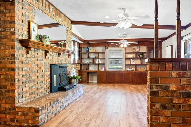 a view of an empty room with wooden floor and windows