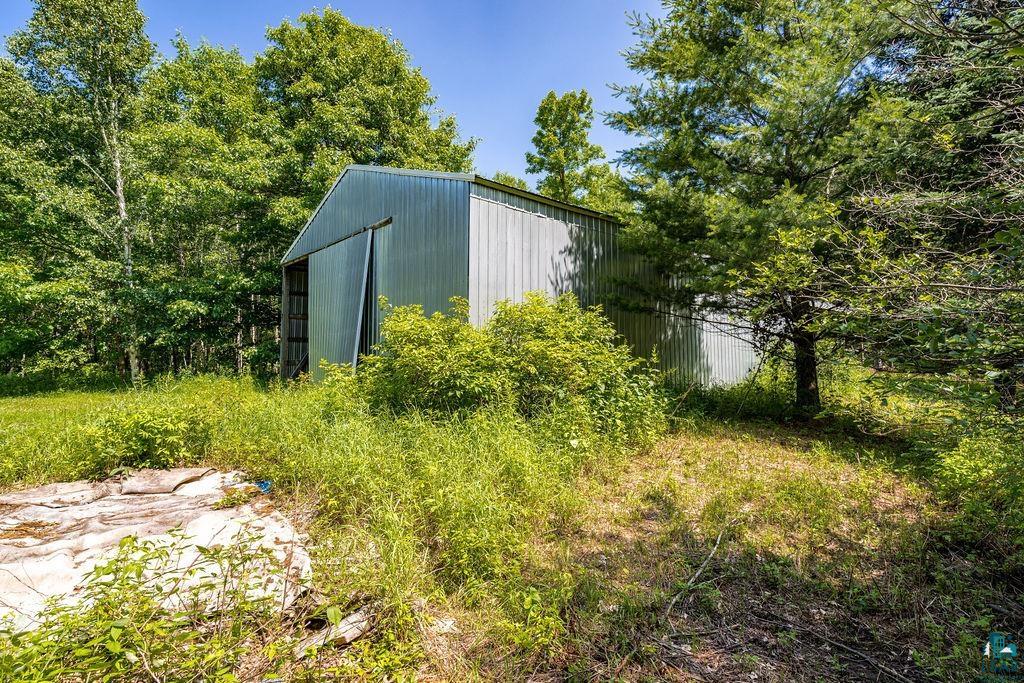 2592 Strandberg Road Barnum, MN 55707 - Photo 19 of 44 Metal utility building with a sliding door, surrounded by mature trees and natural vegetation
