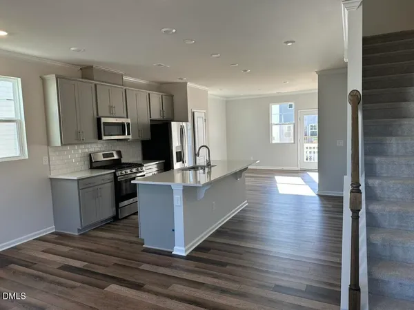 a large kitchen with cabinets wooden floor and stainless steel appliances