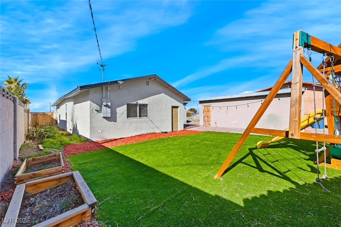 111 Copper Street Henderson, NV 89015 - Photo 16 of 47 Rear view of property with a vegetable garden, stucco siding, and a fenced backyard