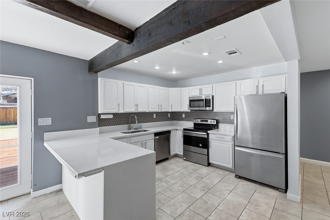 111 Copper Street Henderson, NV 89015 - Photo 3 of 47 Kitchen with stainless steel appliances, white cabinets, a peninsula, recessed lighting, and backsplash