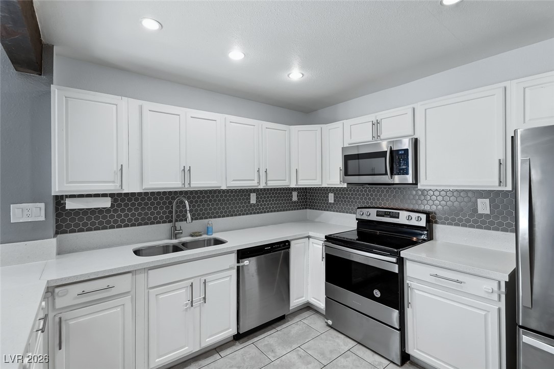 111 Copper Street Henderson, NV 89015 - Photo 39 of 47 Kitchen featuring stainless steel appliances, white cabinets, light tile patterned flooring, and recessed lighting