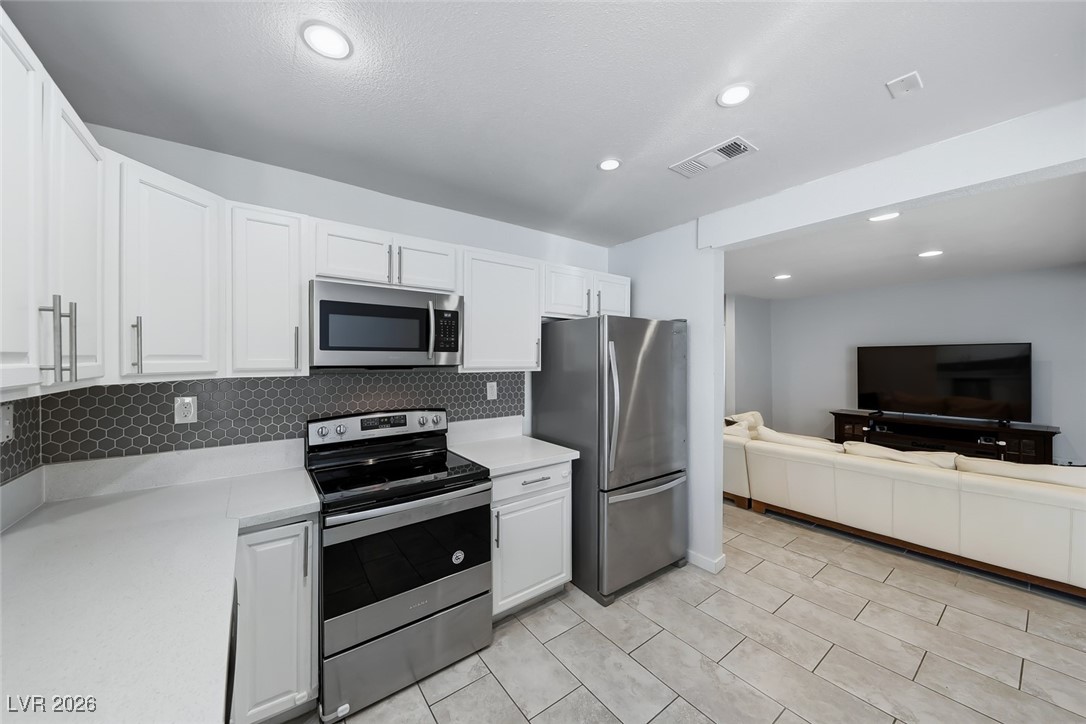 111 Copper Street Henderson, NV 89015 - Photo 46 of 47 Kitchen featuring stainless steel appliances, white cabinetry, open floor plan, tasteful backsplash, and recessed lighting